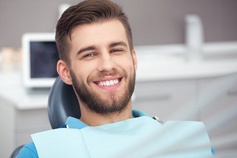 A young man sitting in the dentist’s chair waiting for his regular checkup in Orange