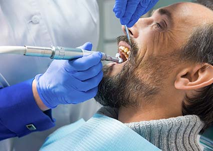 A woman standing in a field and smiling after learning how to prevent dental injuries by her emergency dentist in Orange