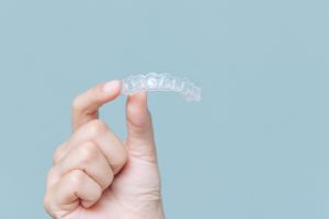 Patient holding an Invisalign aligner.