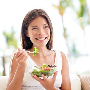 Young woman smiling while eating salad outside