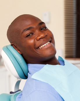 Man in dental chair smiling after getting dental implants in Orange 