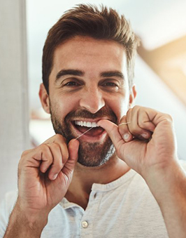 a man smiling while flossing in the morning