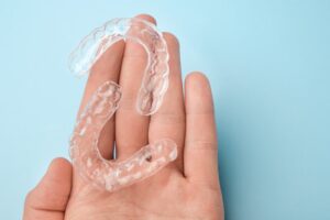 A close-up of a hand holding clear aligners