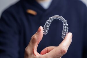 Dentist in navy scrubs holding Invisalign