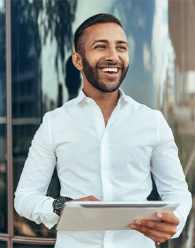 Man smiling while holding tablet outside