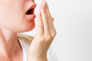 Close-up of woman using hand to check breath