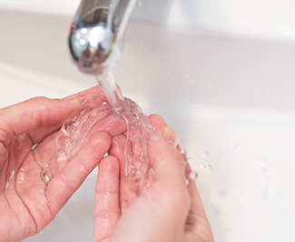 Patient rinsing clear aligner in sink