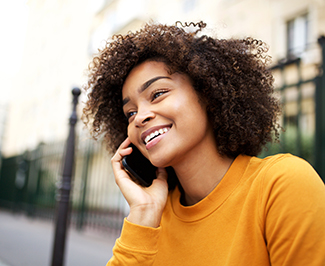 Woman smiling while talking on phone outside