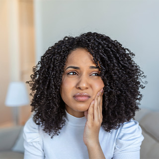 Woman experiencing toothache at home.
