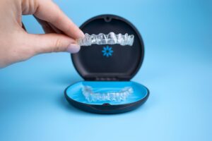 Fingers lifting Invisalign tray from its case