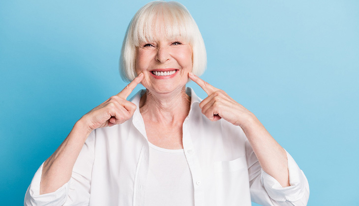 A dental patient pointing to her smile.
